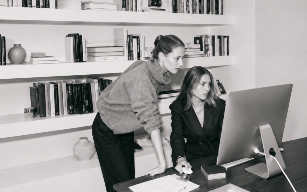 Two PR professionals reviewing campaign performance at a desktop workstation