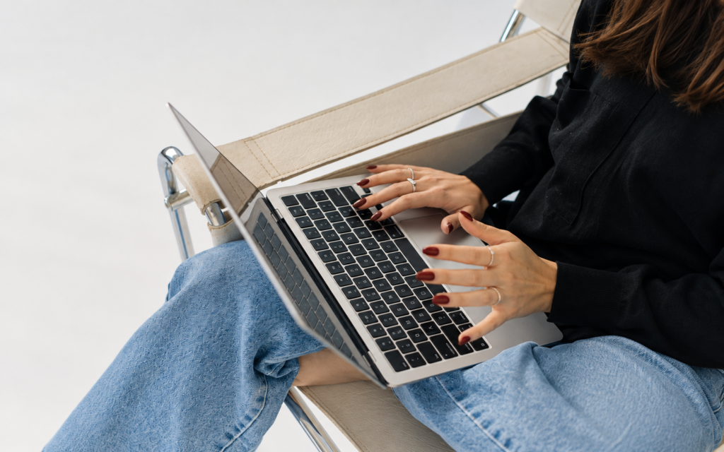 Close-up of hands using a laptop resting on a person's lap.