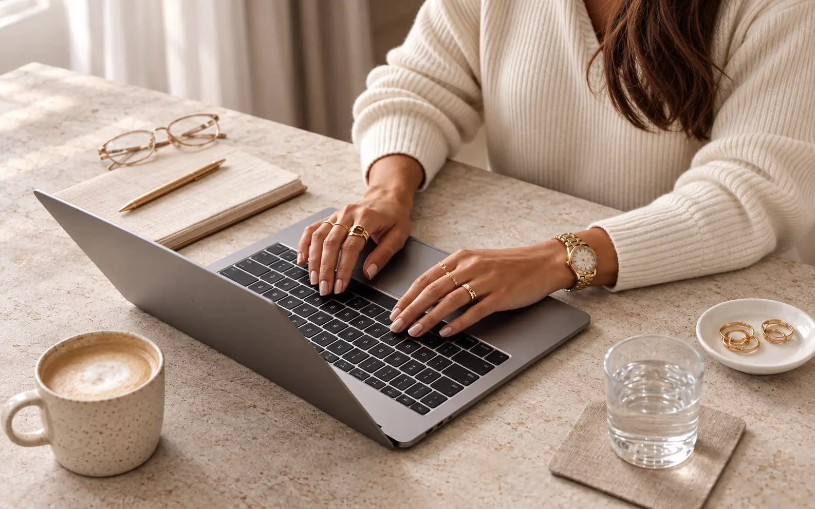 Hands typing on a laptop at a desk with coffee and a notebook suggesting geo vs seo ai strategy.