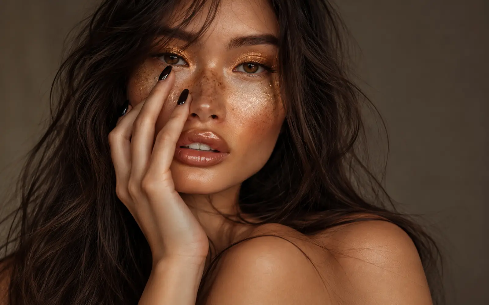 Close-up beauty portrait of a freckled woman with glossy lips and one hand touching her cheek suggesting Rising Customer Acquisition Costs